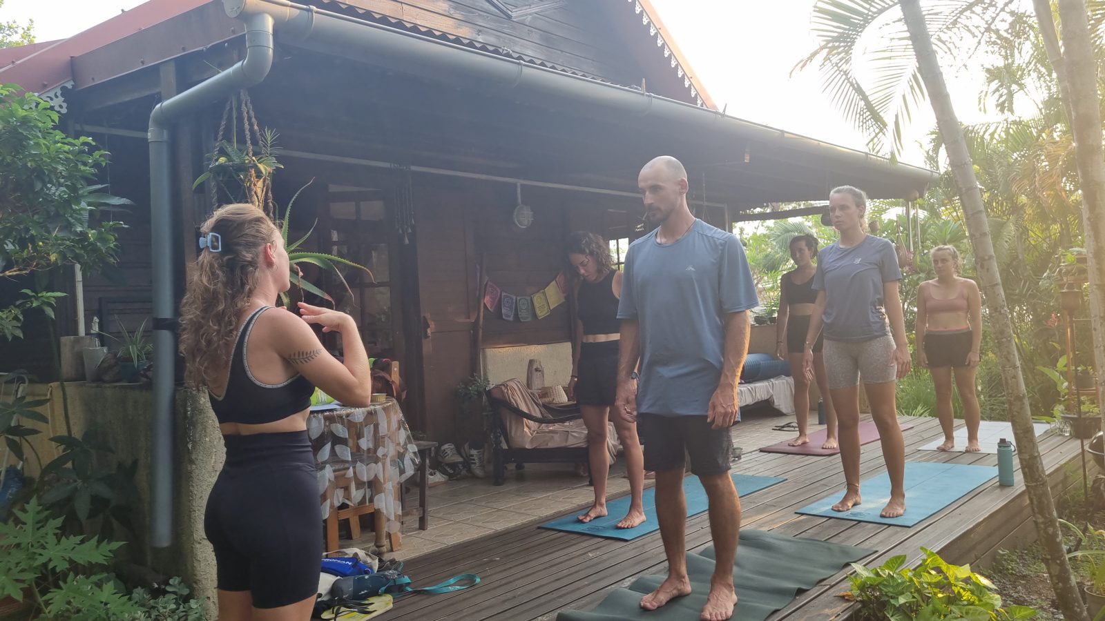 Cours de yoga collectif sous une terrasse en bois